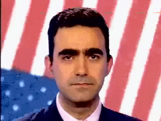 a man in a suit and tie stands in front of a red white and blue american flag