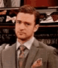 a man in a suit and tie is looking at the camera with a serious look on his face .