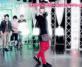 a man in red pants is dancing on a stage in front of a sign that says ' a ' on it