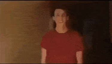 a blurry picture of a man in a red shirt standing in a room .