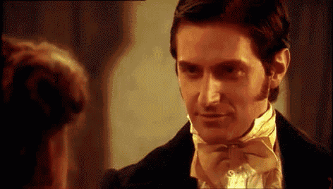 a man in a tuxedo and bow tie looks at a woman