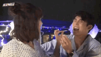 a man is feeding a woman a piece of food while they are laughing .