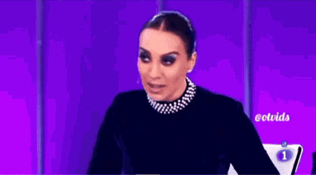 a woman is sitting in front of a purple background and says y no llore