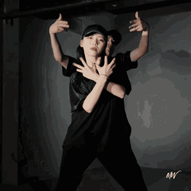 a woman in a black shirt is dancing with a man in a black hat behind her