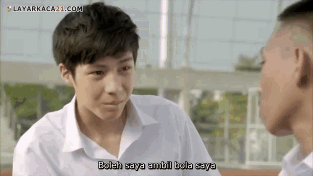 a boy in a white shirt is talking to another boy in a foreign language