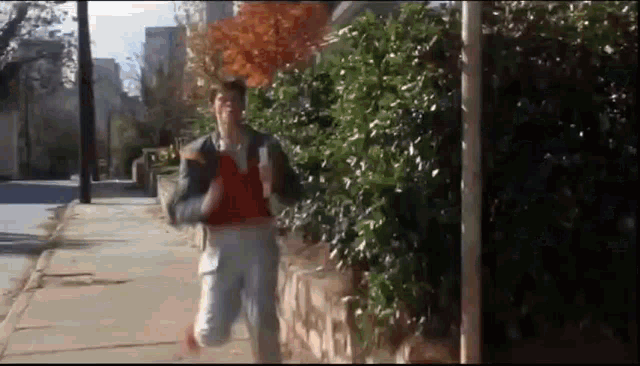 a man is running down a sidewalk while holding a cup of coffee .