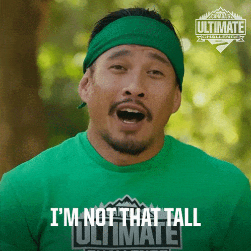 a man wearing a green shirt that says i 'm not that tall on it