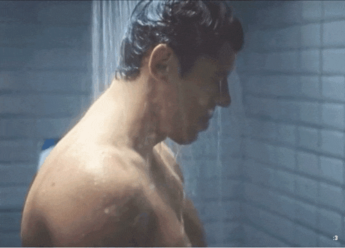 a shirtless man is taking a shower in a bathroom with a shower head .