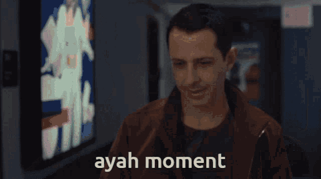 a man in a brown jacket says " ayah moment " on the screen
