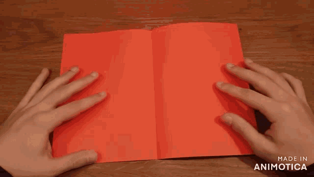 a person is holding a piece of red paper with the words made in animatica on the bottom right