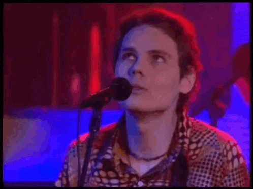 a man is singing into a microphone while playing a guitar in a dark room .