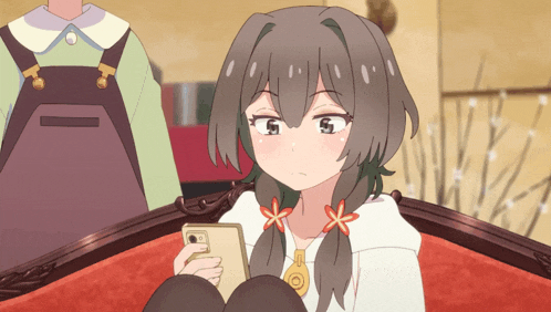 a girl is sitting on a red chair looking at her phone