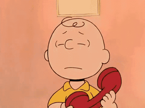 charlie brown from peanuts is talking on a red telephone .
