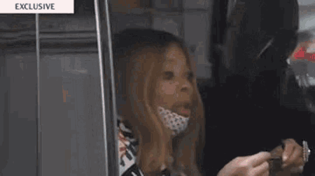 a woman wearing a mask is looking out of a car window and holding a pen .