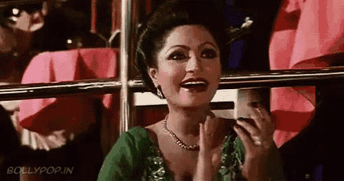 a woman in a green top and necklace is clapping her hands in a room .