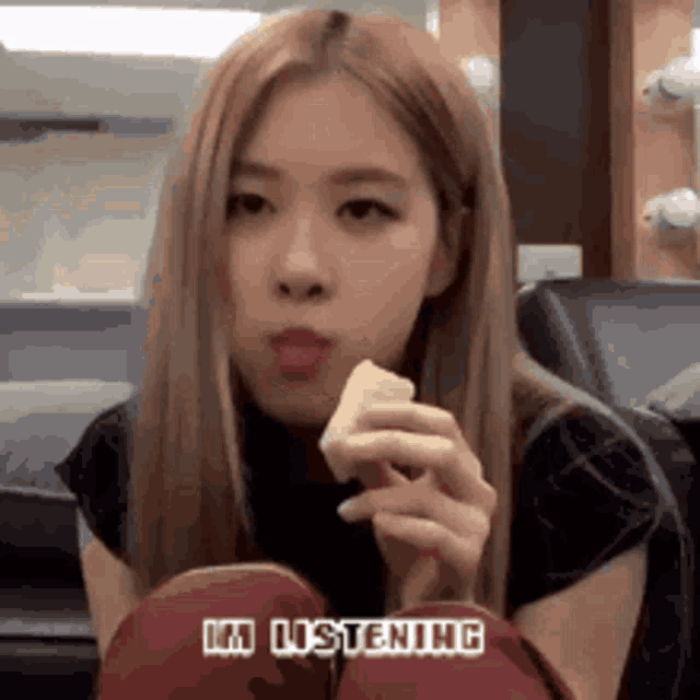 a woman with long blonde hair is eating a piece of food while sitting on a chair .