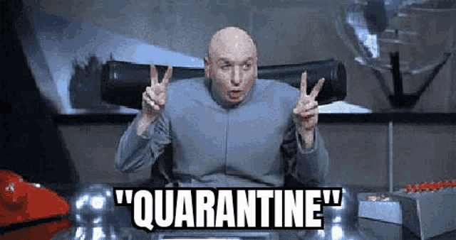 dr. evil is sitting at a desk giving the peace sign .