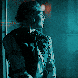 a woman is standing in a dark room with a blue background