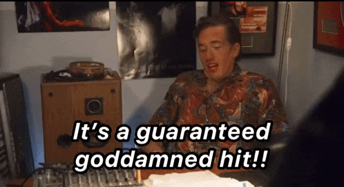 a man is sitting at a desk with the words it 's a guaranteed goddamned hit