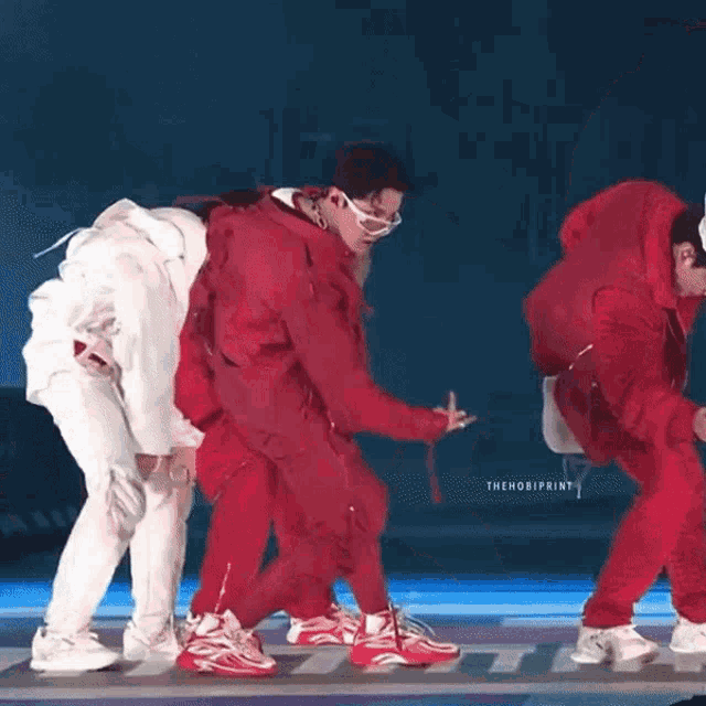 a group of men are dancing on a stage in red and white outfits .