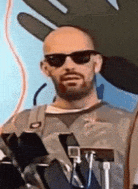a bald man with a beard is wearing sunglasses and a hat