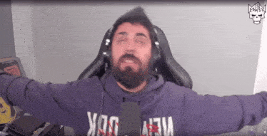 a man with a beard is wearing headphones and a purple hoodie with the word new on it