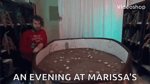a man in a merry christmas sweater sits in front of a circular table with coins on it .