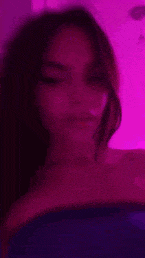 a blurry picture of a woman 's face in front of a purple light .