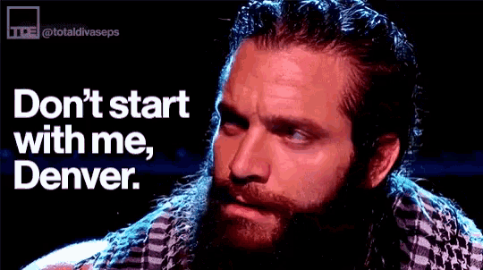 a man with a beard is standing in front of a sign that says do n't start with me denver