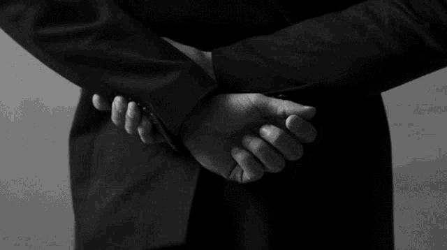 a man in a suit holds his hands behind his back