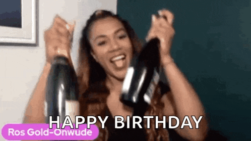 a woman is holding two bottles of champagne in her hands and says `` happy birthday '' .