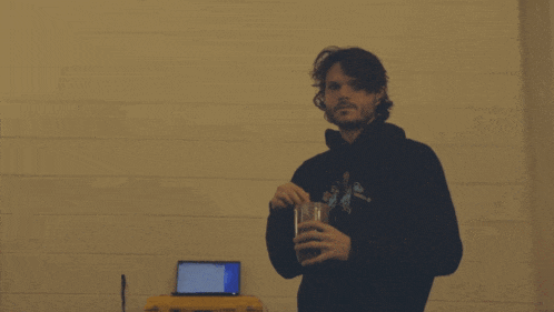 a man wearing a hoodie that says ' a ' on it holds a glass