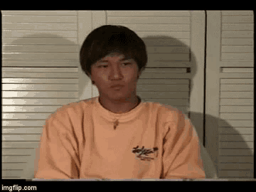a young man wearing an orange sweatshirt is sitting in front of a white door .