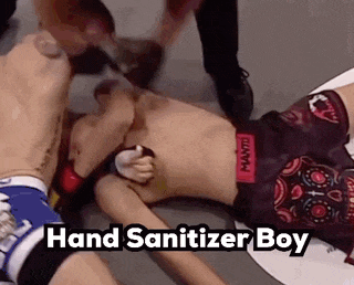a man is laying on the ground with a hand sanitizer in his mouth while fighting another man .