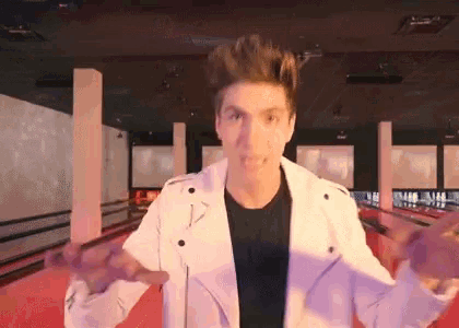 a man in a white jacket stands in front of a bowling alley