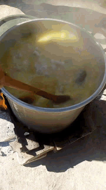 a wooden spoon is stirring a large pot of food