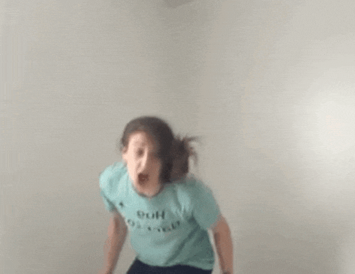 a woman in a blue t-shirt is jumping in the air .