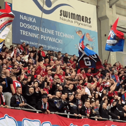 a crowd of people in a stadium with a sign that says " swimmers "