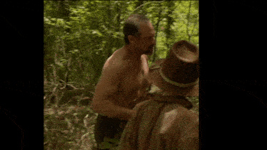 a man without a shirt is walking through a forest