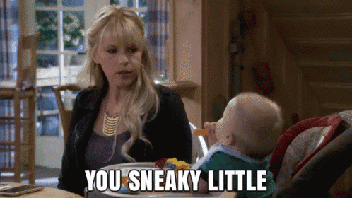 a woman is sitting at a table with a baby and says " you sneaky little "
