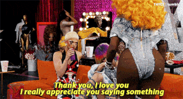 two drag queens sitting on a couch with one saying thank you