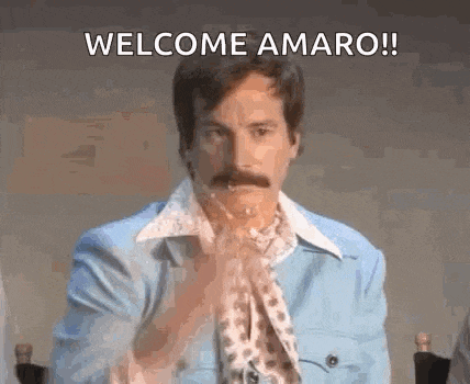 a man with a mustache is wearing a blue jacket and a scarf and says welcome amaro !
