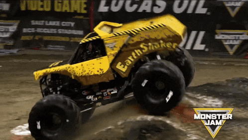 a yellow monster jam truck is driving through the mud