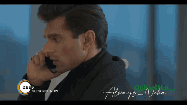 a man talking on a cell phone with a zee5 subscribe now advertisement in the background