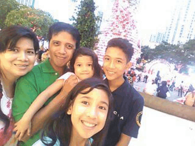 a group of people posing for a picture in front of a christmas tree .