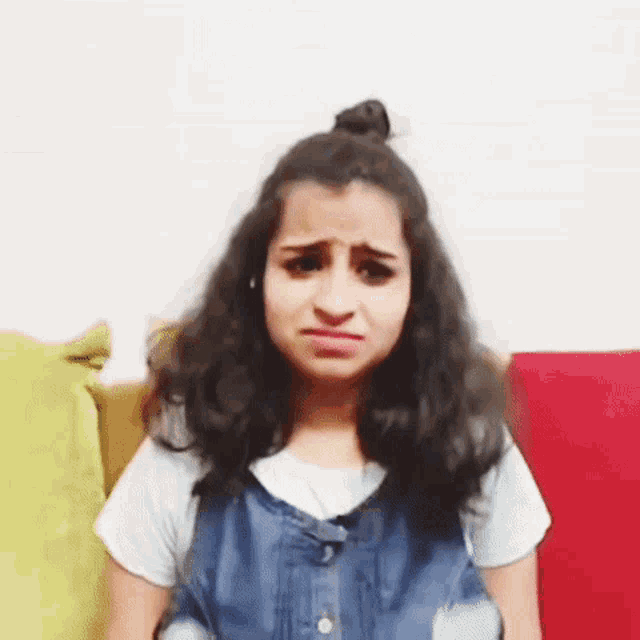 a woman is sitting on a couch making a funny face .
