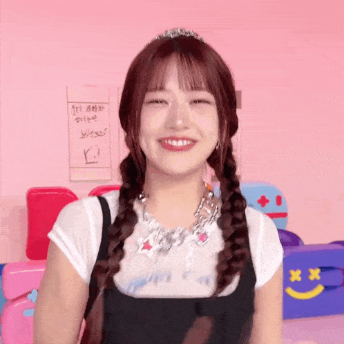 a girl with pigtails and a tiara on her head is smiling and looking at the camera .