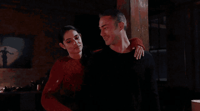 a woman is hugging a man in a dark room