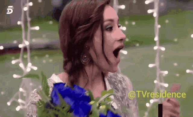 a woman is holding a bouquet of blue flowers with her mouth wide open