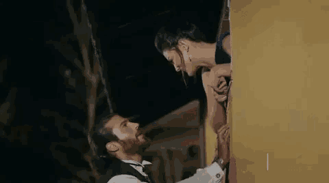 a man and a woman are standing next to each other in front of a building at night .